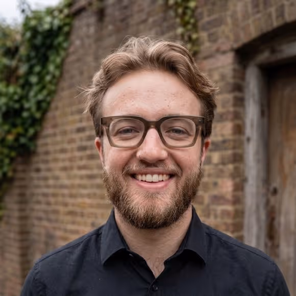 Emiel Hemmes, smiling in a dark shirt against a brick wall